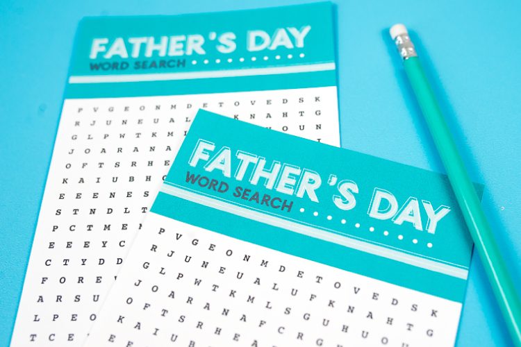 A close up of a pencil and two pieces of paper that have a Father\'s Day word search printed on them