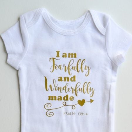 A white onesie decorated with the saying, "I am fearfully and wonderfully made - Psalm 139:14"