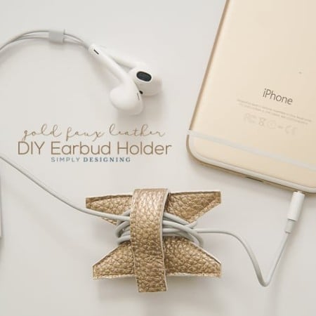 Earbuds wrapped around a gold faux leather earbud holder and plugged into an iPhone with advertising by Simply Designing for a DIY Earbud Holder