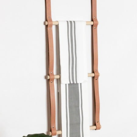 A ladder made from wood and leather with towels hanging from it