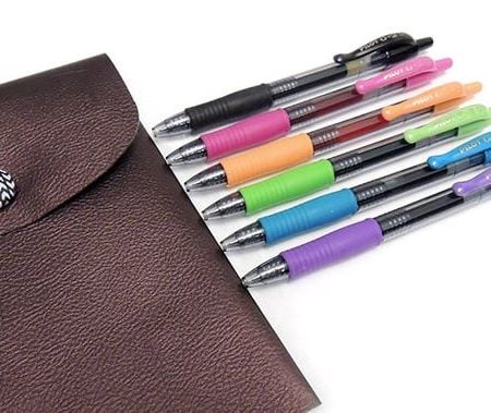 Leather pouch with 6 pens lying next to it