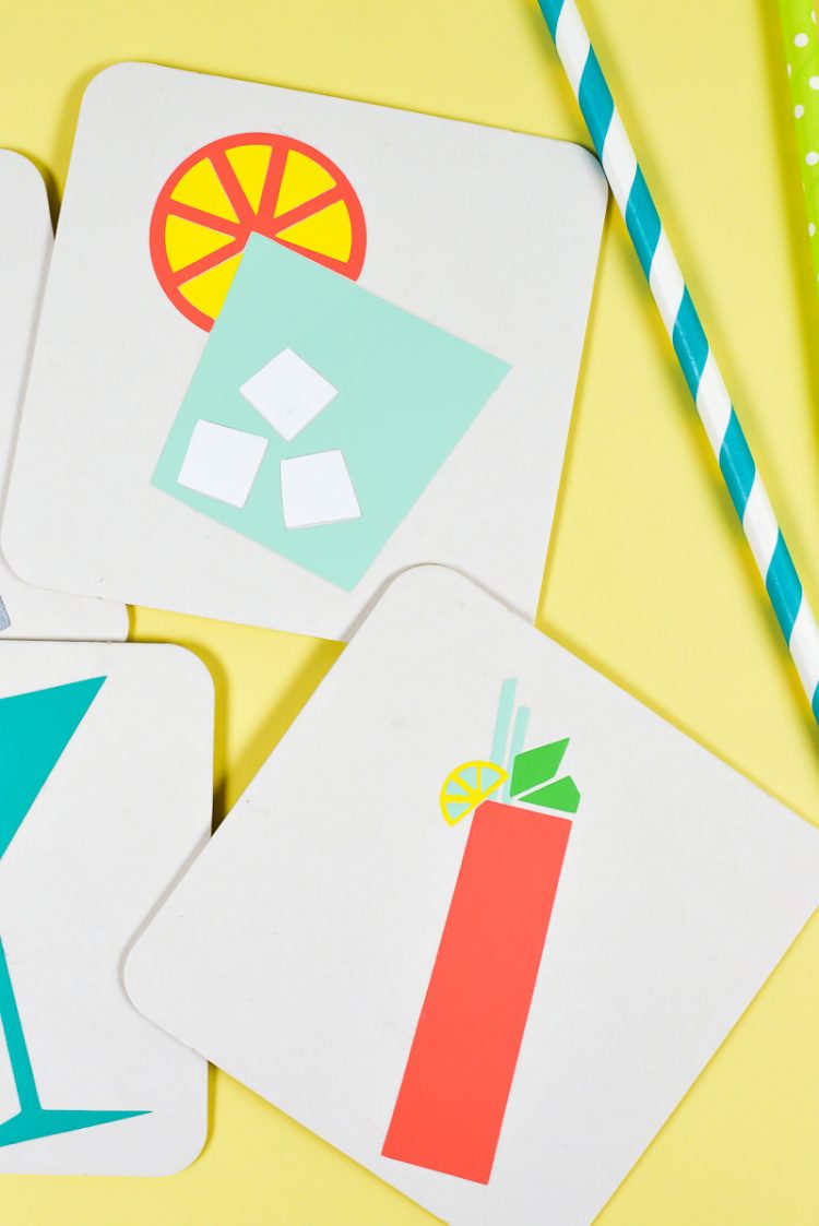 A drinking straw and white coasters decorated with images of a glass of ice, an orange slice and a tall cocktail glass