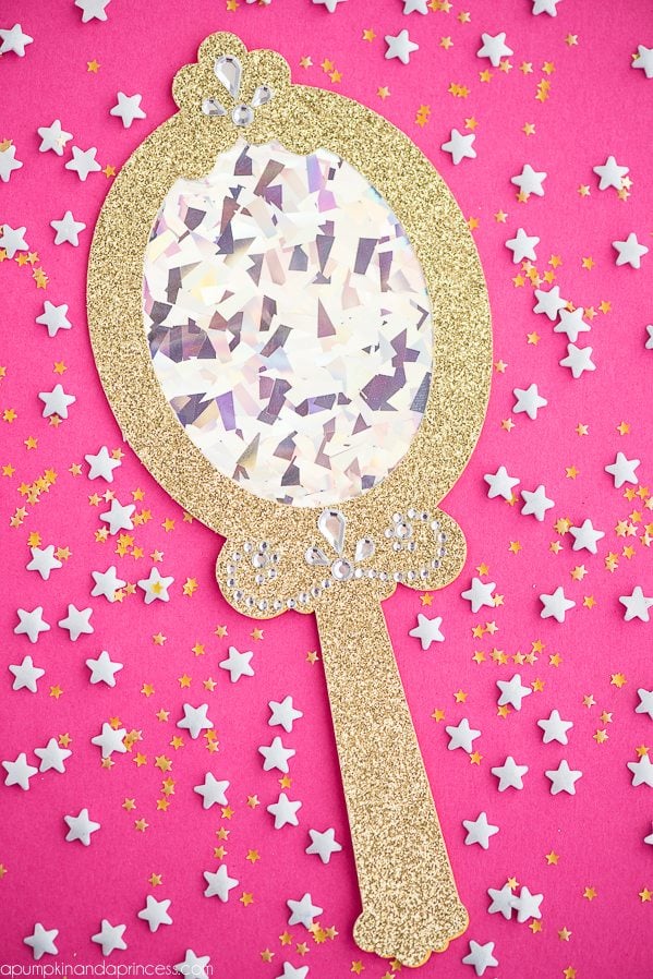 An image of a gold mirror surrounded by white and yellow stars against a pink background