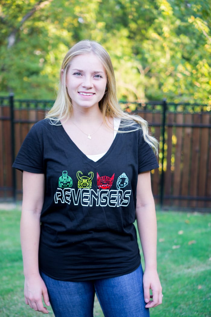 A woman standing outside and wearing a black t-shirt with images of the Avengers on it