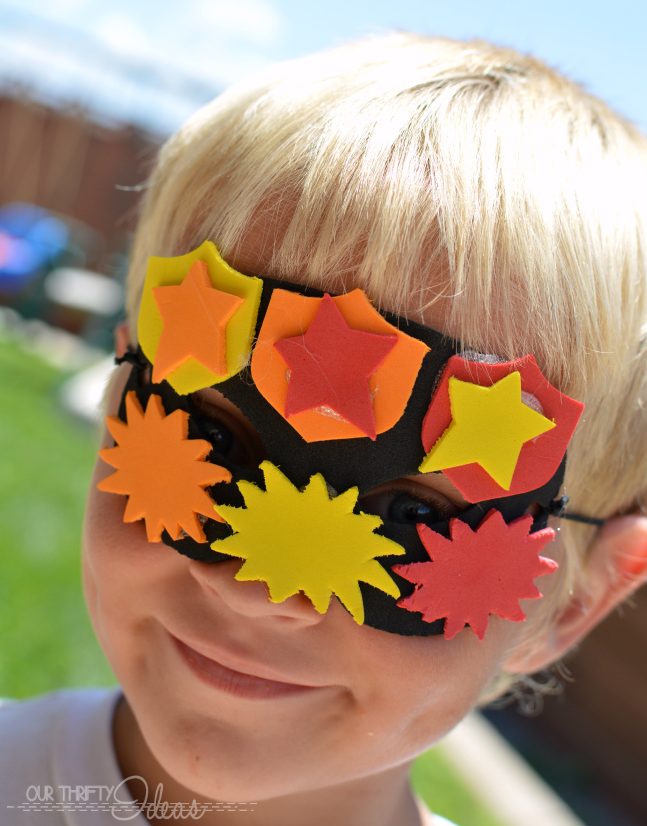 A young boy wearing a decorated superhero mask