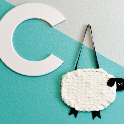 The letter "C" and A yarn and felt sheep hanging on a wall