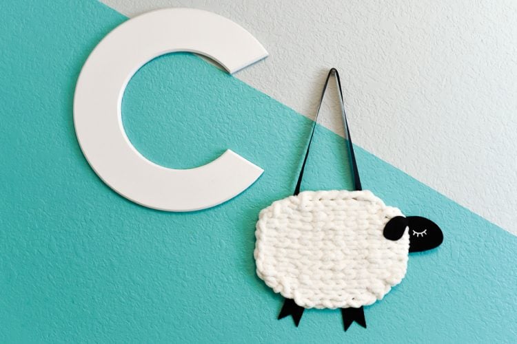 The letter \"C\" and A yarn and felt sheep hanging on a wall