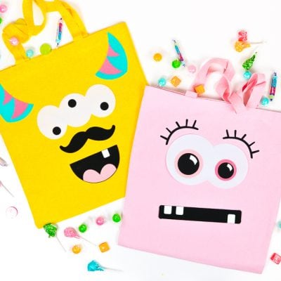 Pieces of candy around a yellow and a pink bag both decorated with funny faces
