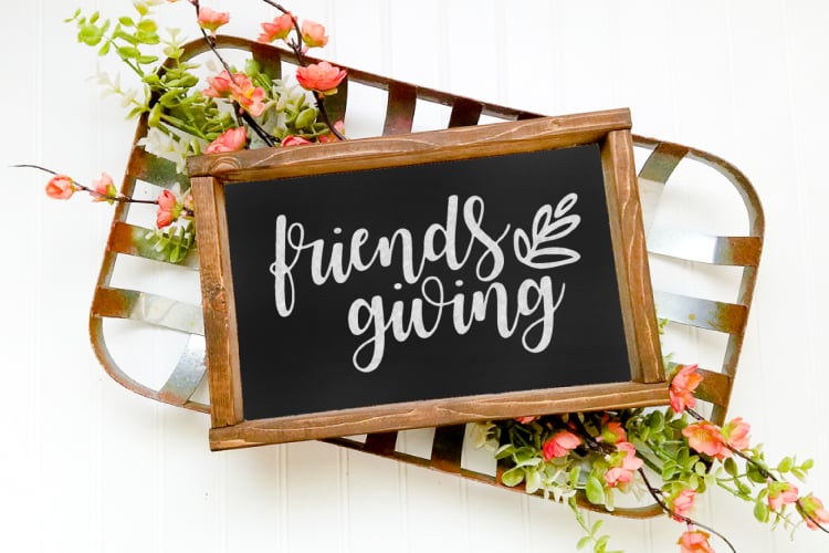 Flowers surrounding a \"Friends Giving\" sign in a wooden frame