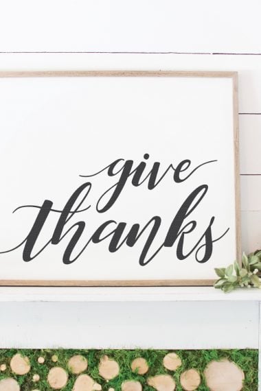 A wood framed white sign that says, "Give Thanks"