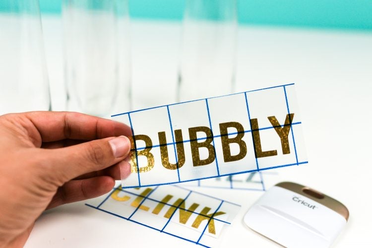A hand holding up a vinyl cutout that says, \"Bubbly\"