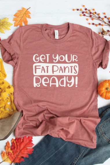 Fall decor, a pair of blue jeans and a rust-colored t-shirt with an image that says, "Get Your Fat Pants Ready!"