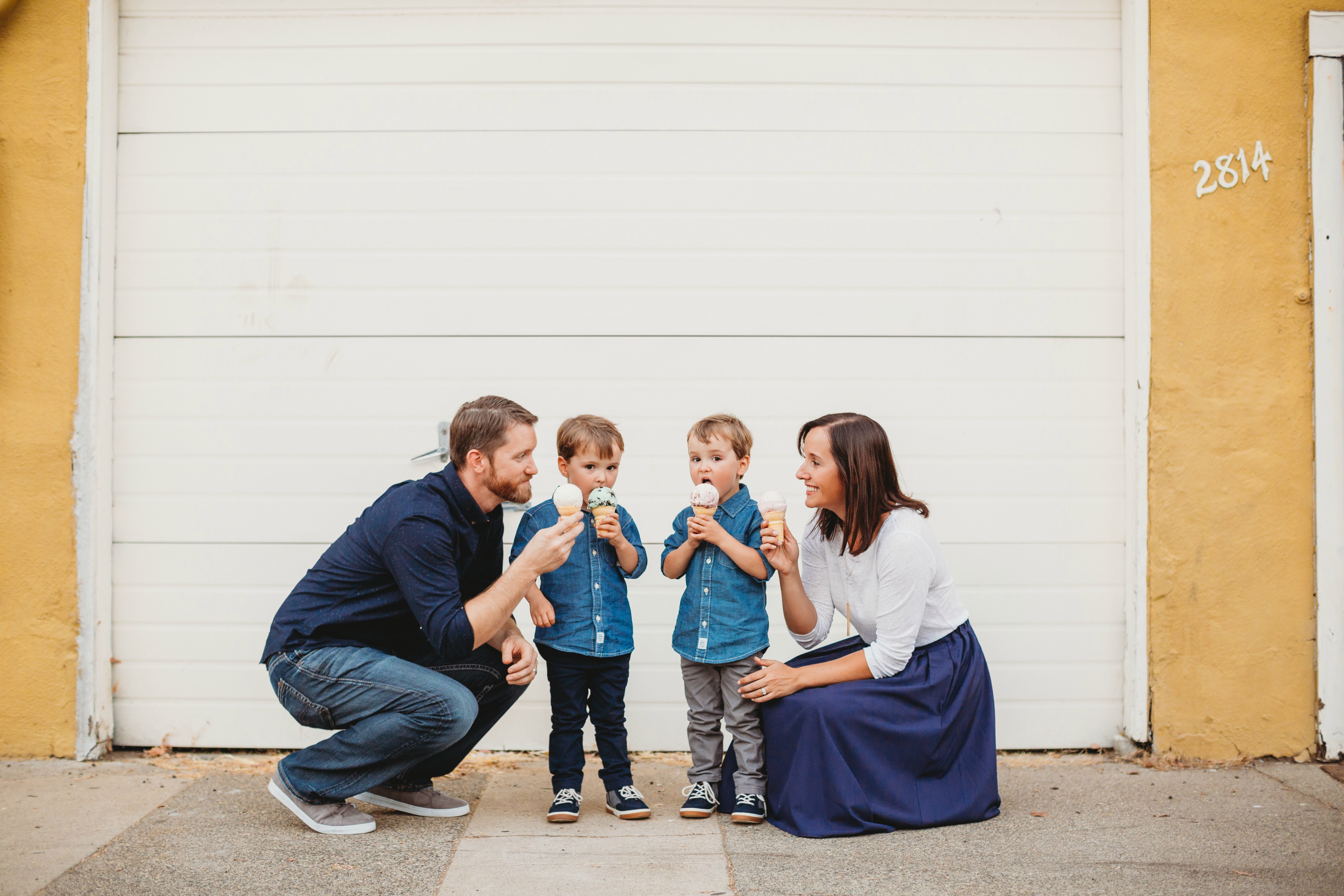 Cori, with her two little boys and her husband all eating ice cream cones in front of a white garage door