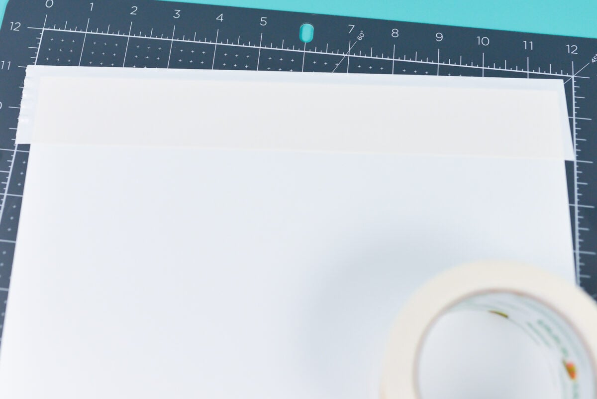 Close up of a gray mat holding a piece of white paper that is taped to the mat