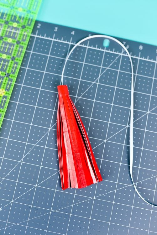Red material on a gray mat that is rolled up to look like a tassel