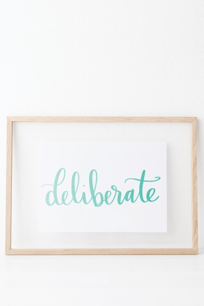 The word "Deliberate" on a piece of white paper and framed with a wooden frame