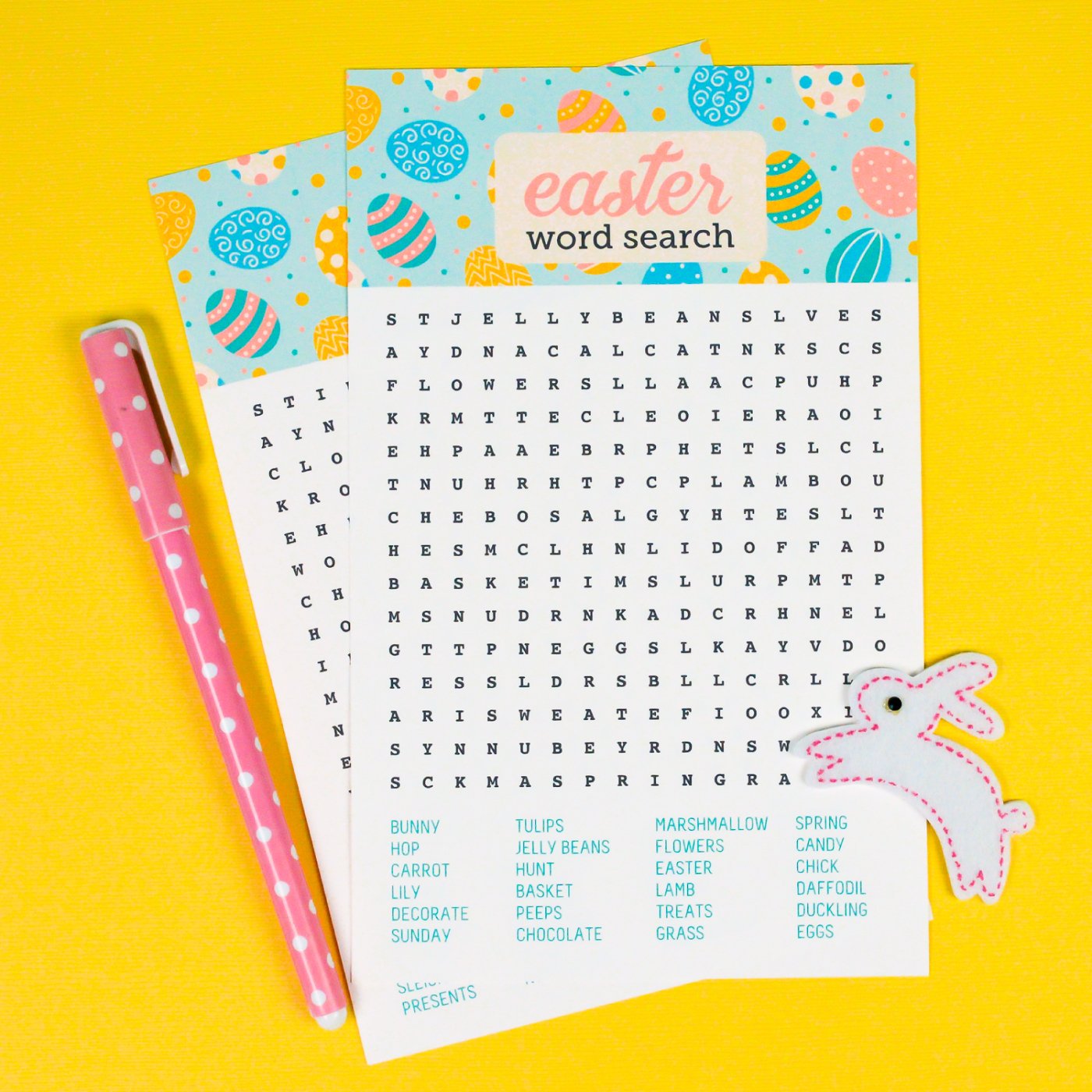 A pink polka dotted pen sitting next to two Easter Word Search papers