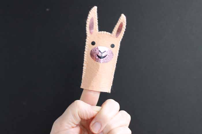 A close up of a person\'s hand with a llama finger puppet in it