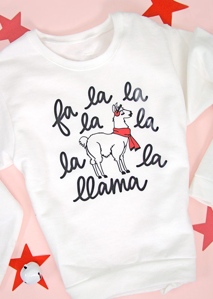 A white t-shirt decorated with an image of a llama and a saying, \"fa la la la la la la llama\"