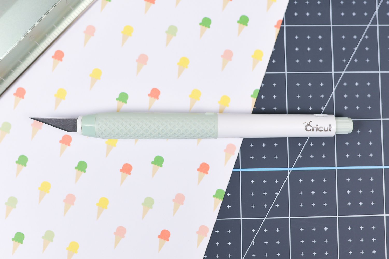 Close up of the Cricut True Control Knife, a cutting ruler and a piece of fabric on top of the Cricut self-healing mat