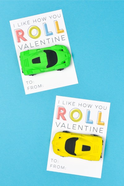 Two Valentine cards, one with a yellow toy car attached to it and the other one with a green toy car and both say, "I Like How You Roll Valentine"