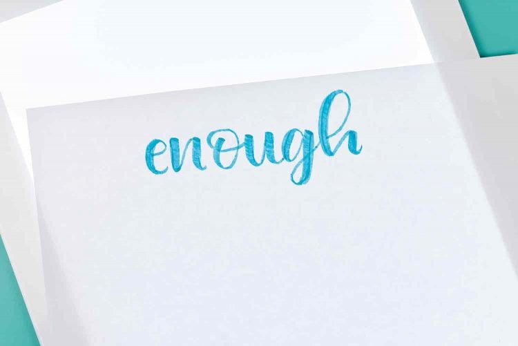 A Cricut Brightpad with a piece of paper on top of it with the word \'enough\' written on it
