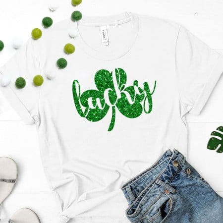 White t-shirt with a glittery green shamrock on it and the word lucky