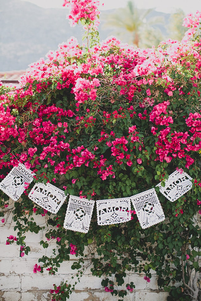 A bush with pink flowers with a hanging wedding themed banner on it