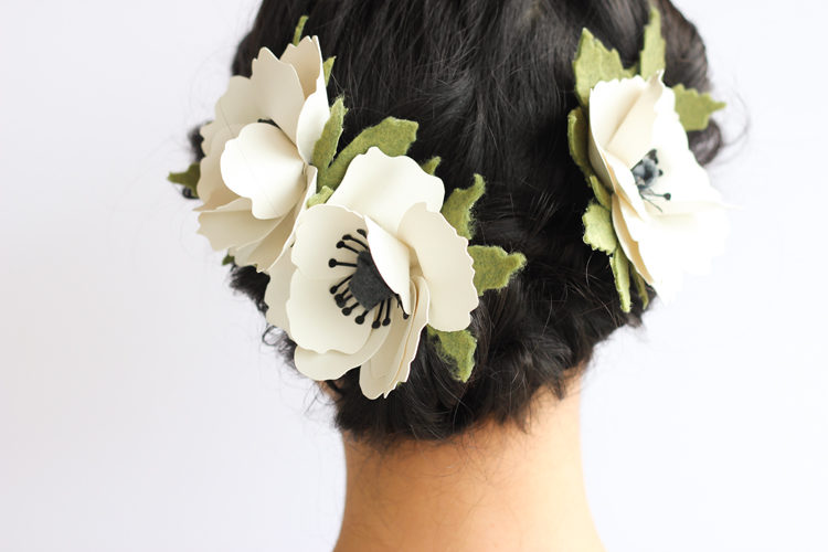 The back of a woman\'s head with paper cut flowers in her hair