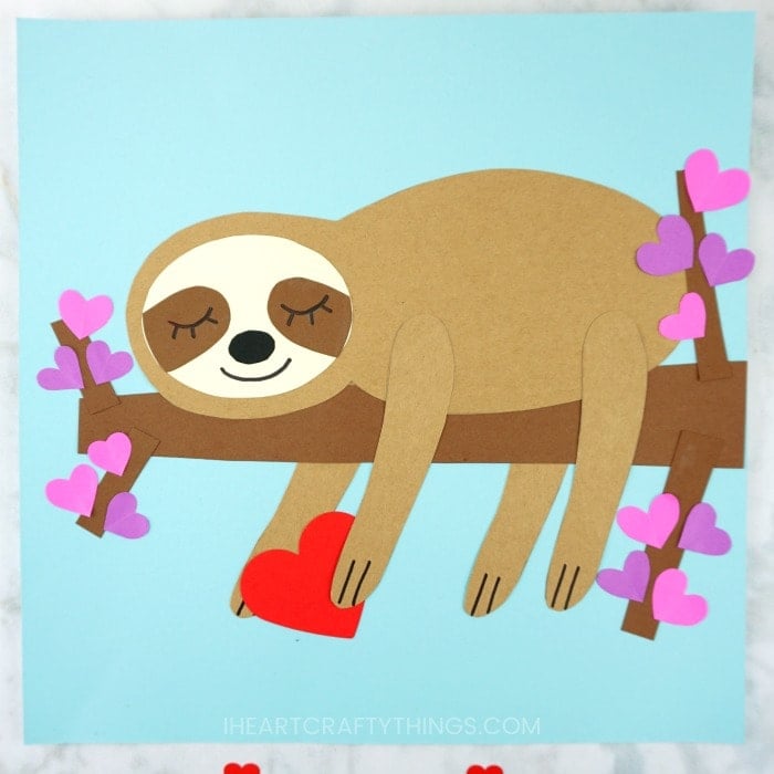 Sloth sleeping on a tree branch holding a red heart