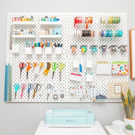 A pegboard hanging on a wall and filled with crafting tools