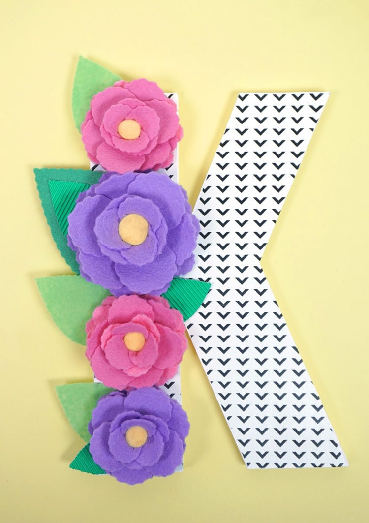 The letter \"K\" decorated with paper flowers and leaves
