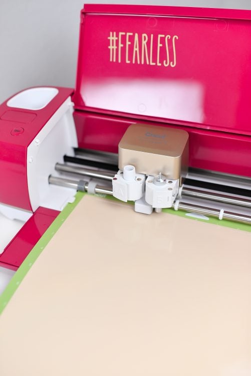 A cricut machine loaded with a mat and piece of vinyl