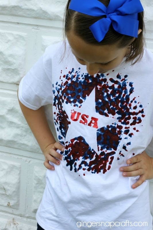 A girl wearing a blue bow in her hair and a white t-shirt decorated with a 4th of July image