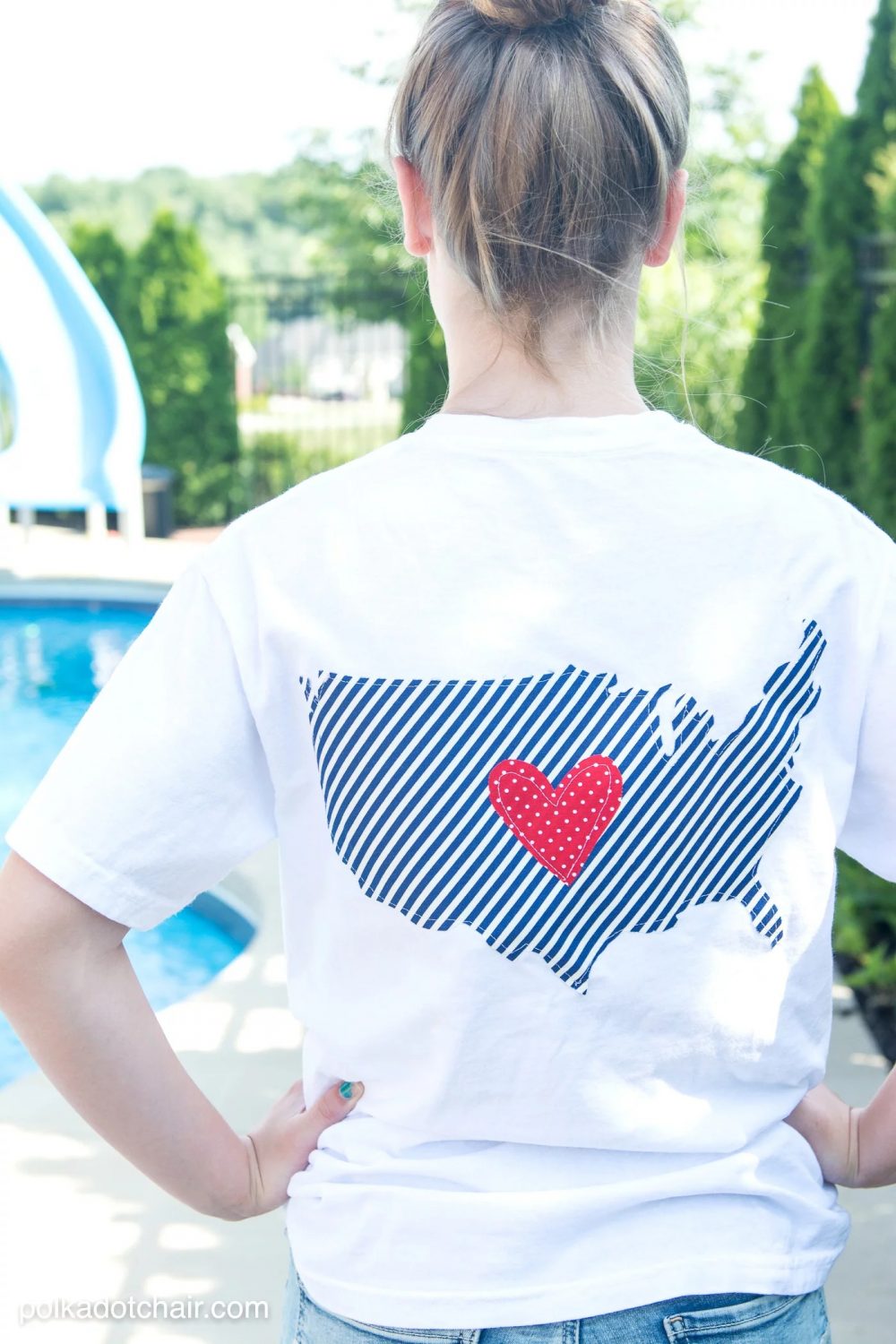 A person wearing a white shirt with an image on the back of the shirt of the USA outline and a red heart in the middle