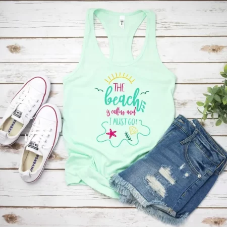 A mint green tank top that says, The Beach is Calling and I Must Go