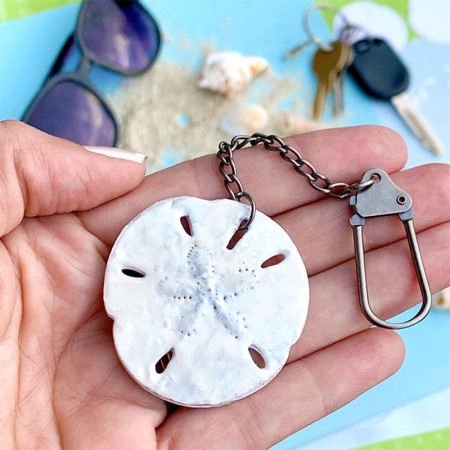 A person holding a faux sand dollar key chain