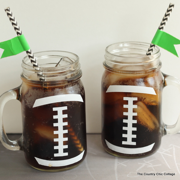 Two Mason jars with handles filled with a refreshment and decorated with the stitching as seen on a football