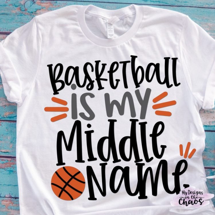 An aqua blue distressed table holding a white t-shirt decorated with a basketball and the saying, \"Basketball is my Middle Name\"