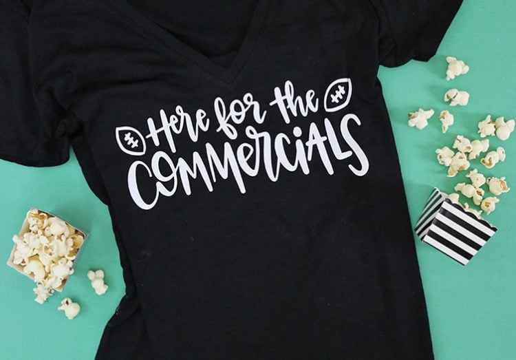 Popcorn scattered about a black shirt with the saying \"Here for the Commercials\'