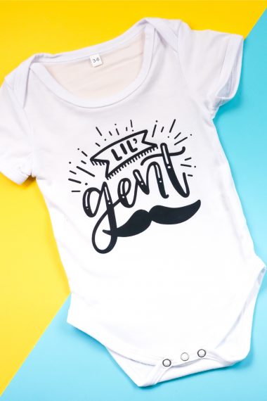 A white onesie decorated with a mustache and the saying, "Lil" Gent"