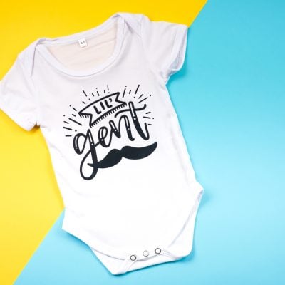 A white onesie decorated with a mustache and the saying, "Lil" Gent"