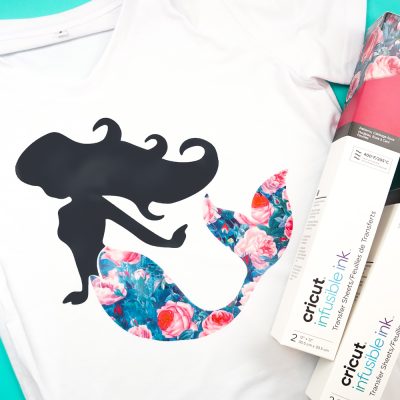 A white t-shirt with an image of a mermaid on it and two boxes of Cricut infusible ink by the shirt