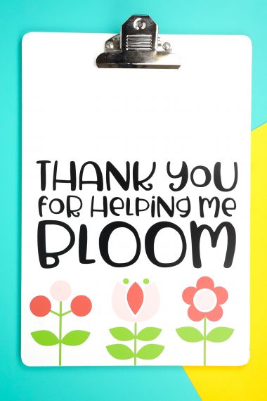 An image of a clipboard decorated with flowers and the saying, "Thanks you for Helping Me Bloom"