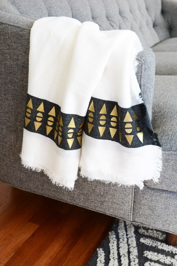 A decorated throw blanket hanging over the arm of a sofa