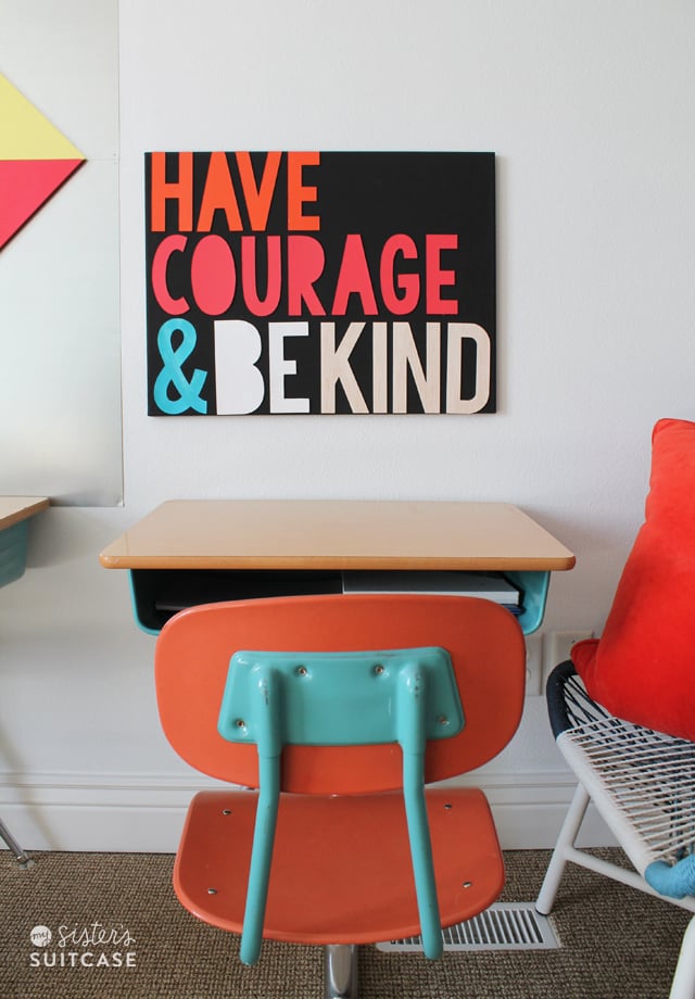 A school desk with a sign above it that says, \"Have Courage & Be Kind\"