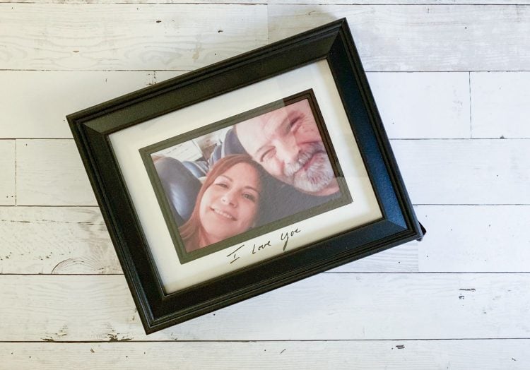 A framed picture of a man and woman with the words \"I Love You\" written on the mat surrounding the picture