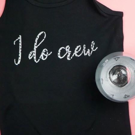 A wine glass and woman's black tank top with the saying, "I Do Crew"