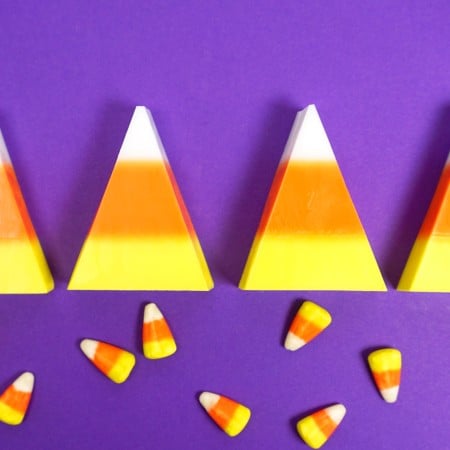 Real candy corn candy next to candy corn looking soap against a purple background