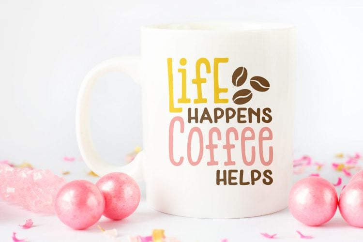 Pink ornaments and confetti surrounding a coffee cup with the saying, \"Life Happens Coffee Helps\"